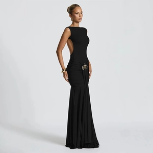 Detail of elegant backless black dress featuring ruching and gold metal flower pin