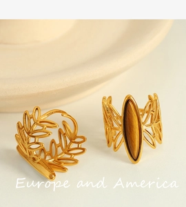 Detail of vintage gold-plated titanium steel rings featuring leaf design and tiger eye stone