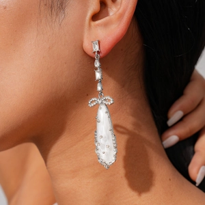 Gros plan de boucles d'oreilles nœud papillon avec zircon et pendentif goutte blanc perle