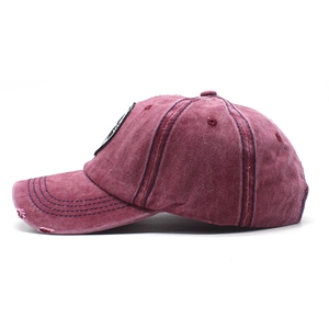 Detail of vintage washed red baseball cap with distressed brim and contrast stitching