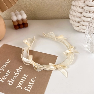 Close-up of cream white chiffon headband with ribbon bow tie in a cozy aesthetic setting