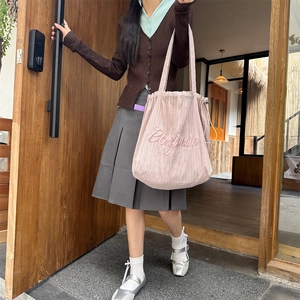Detail of pink striped corduroy tote bag with Bonjour embroidery and drawstring closure
