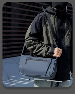 Outdoor functional grey-blue messenger bag in durable nylon worn by a male model
