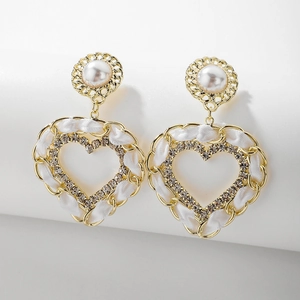 Détail de boucles d'oreilles cœur avec ruban blanc tressé, perles et cristaux