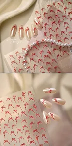 Détail d'autocollants nœud rouge sur ongles perle et feuille transparente aux lignes fluides