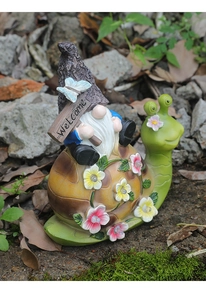 Detail of waterproof resin gnome riding a snail garden statue with welcome sign and solar lights