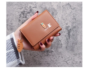 Detail of compact brown PU leather tri-fold wallet with carrot rabbit charm in hand