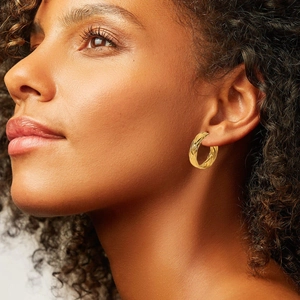 Close-up of 18K gold-plated stainless steel C-shape earrings with spiral texture on model