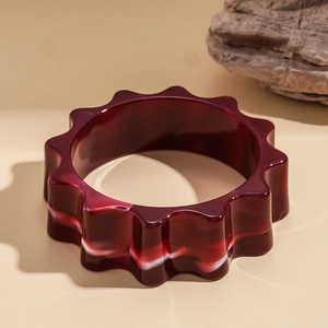 Dettaglio macro del bracciale a fiore in acrilico con trama marmorizzata rossa e bianca