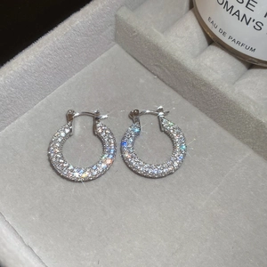 Macro shot of silver zircon U-shaped earrings on grey velvet with brilliant fire reflections