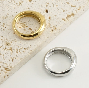 Close-up of gold and silver minimalist rings on natural stone and white background