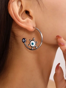 Detail shot of a model wearing a silver evil eye C-shaped hoop earring with blue enamel