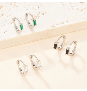 Detailed macro view of S925 sterling silver hoop earrings with emerald and zircon stones