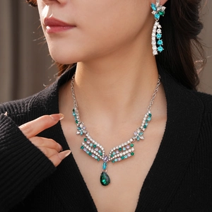Detailed view of vintage silver floral jewelry set with green teardrop pendant on model