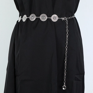 Close-up of silver metal waist chain with hollow round motifs on black dress