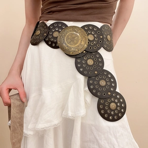 Close-up of retro bohemian waist chain with embossed brass discs and vintage brown leather