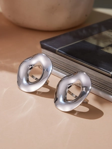Close-up of silver wavy hollow rings with a polished mirror finish on a warm beige surface