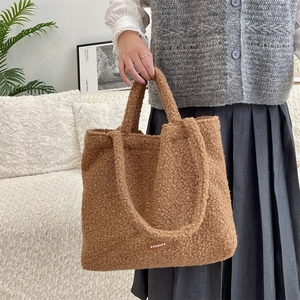 Dettaglio di una borsa tote in pile marrone con etichetta logo e texture morbida