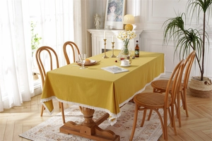 Close-up of mustard yellow cotton tablecloth featuring elegant white lace edges