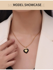 Close-up of heart pendant necklace with black enamel and diamonds on gold bead chain