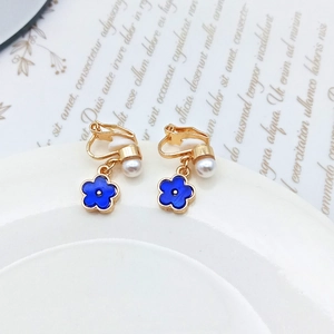 Elegant blue flower clip-on earrings with white pearls and gold setting on ceramic plate