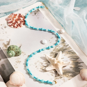 Blue turquoise beaded necklace with gold clasp styled on shells and starfish scene
