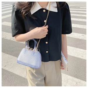 Street style view of light blue PVC mini jelly bag with diamond pattern and chain strap