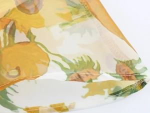 Detailed close-up of sunflower print organza fabric with precise edge stitching