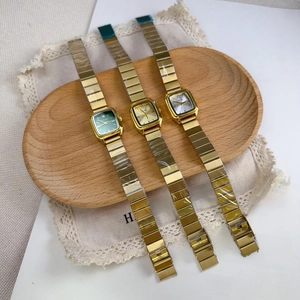 Three square dial quartz watches with gold alloy straps on a wooden tray with lace decor