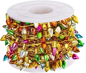 Close-up of colorful teardrop Christmas bulbs on a gold braided string on a white reel