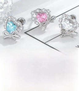 Macro detail of heart-shaped zircon earrings with silver bow and product size chart