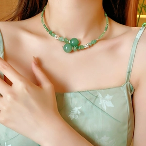 Dettaglio della collana di perline in giada verde con fiori di loto sul collo