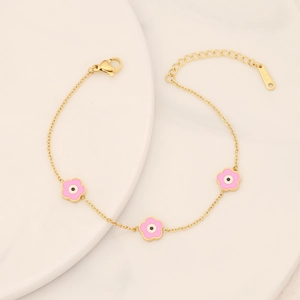 Detail of gold stainless steel bracelet with pink enamel flowers and evil eye motifs