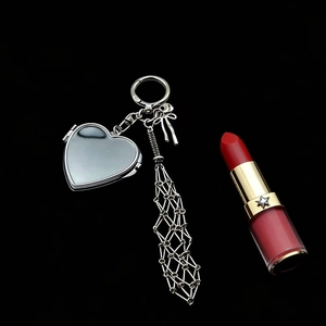 Close-up of silver heart-shaped pendant with woven metal mesh tassel and bow detail