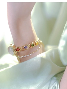 Detail of gold bracelet with multicolor oval gemstones on a model's wrist