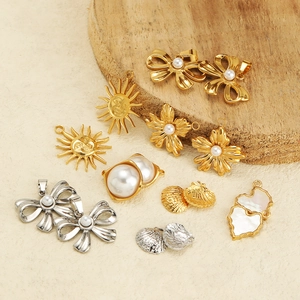 Assorted gold and silver stainless steel pendants with pearls on a wooden display