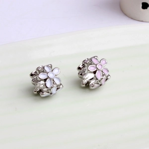 Macro shot of silver peach blossom earrings with pink enamel inlay on ceramic tray