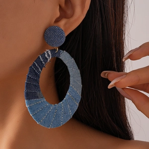Detailed view of oversized oval denim patchwork hoop earrings with retro blue fabric textures