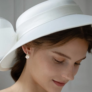 Detail view of elegant pearl stud earrings with zircon-inlaid A-frame on model