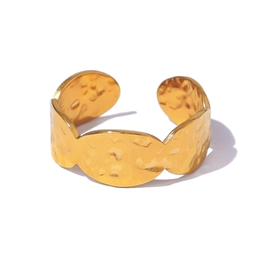 Close-up of golden hammered texture and wavy edges on a stainless steel open cuff bracelet