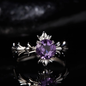 Macro shot of S925 silver ring with a round purple amethyst on a reflective dark surface