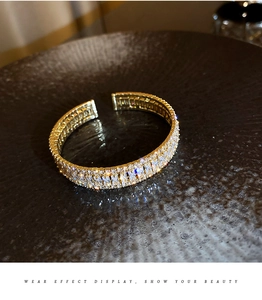 Détail d'un bracelet ouvert doré orné de trois rangées de zircons cubiques et baguettes