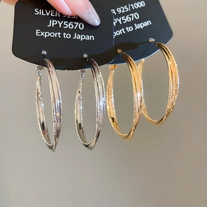 Macro shot of large 18k gold and silver hoop earrings with fine engraved texture detail