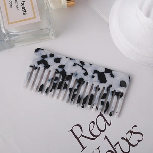 Acetate hair comb with black and white marble pattern in a minimalist lifestyle setting