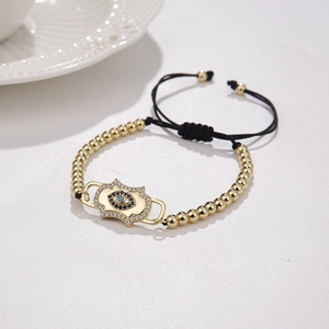 Adjustable golden evil eye bracelet with blue zircon stones and black braided cord