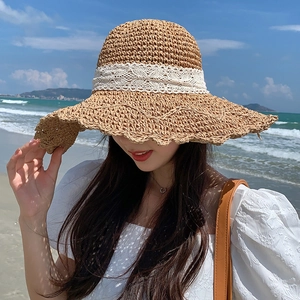 Women's foldable wide-brim straw hat with white lace bow and elegant seaside resort style