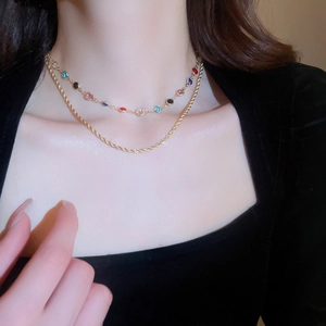 Close-up of double-layered gold necklace with colorful zircon stones worn by a model
