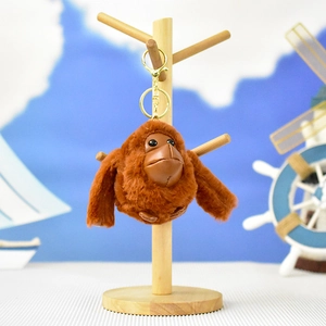 Vista dettagliata di un portachiavi in peluche di orangotango marrone su un supporto legno.