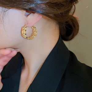 Detailed view of gold-plated link hoop earrings worn by a model for a stylish look
