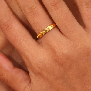 Close-up of gold stainless steel ring with fish scale texture on woman finger